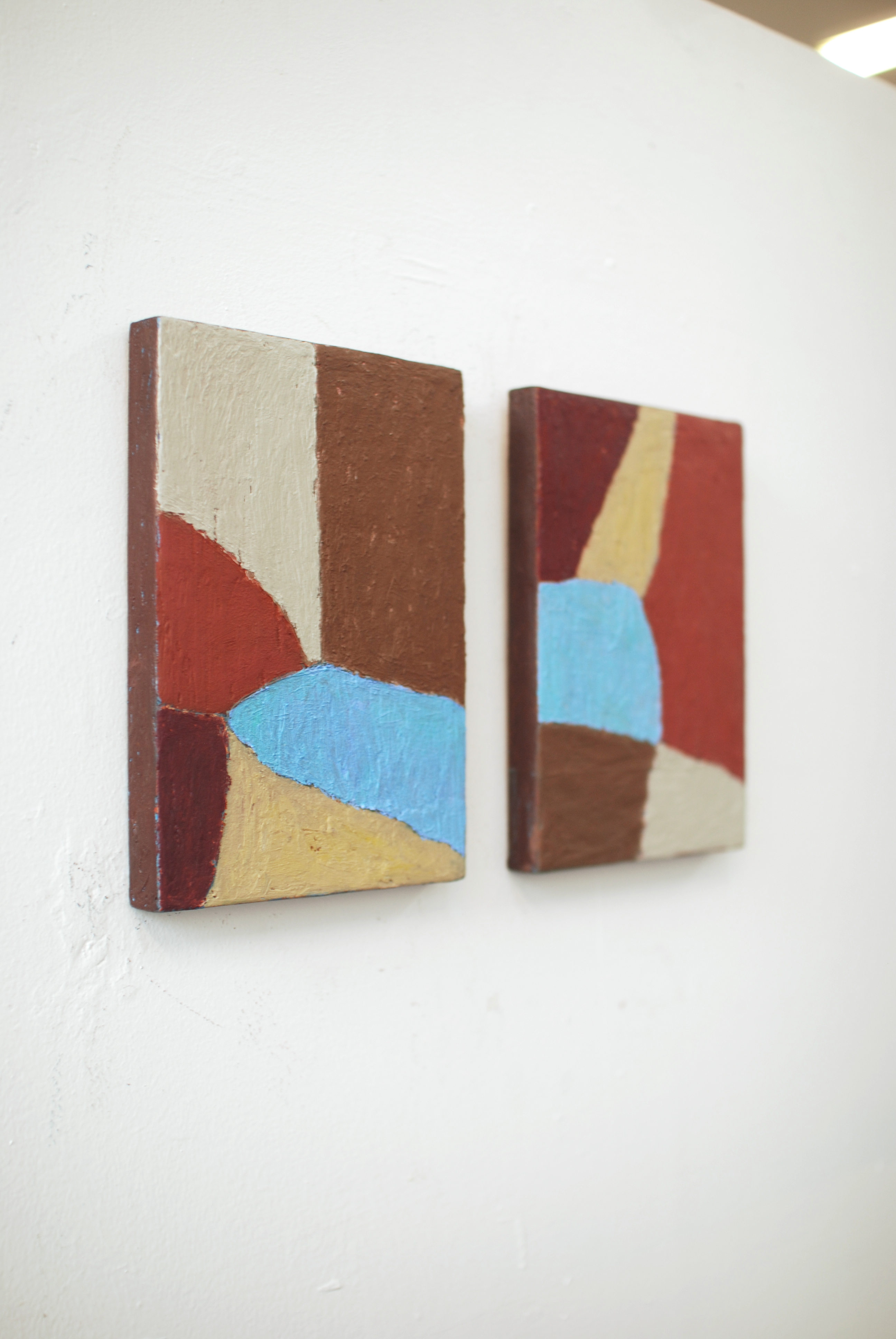 Two abstract art pieces on a white wall